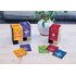 A photo of different Happiness Is tea packs. They are on a table and there is also a plant on the table.